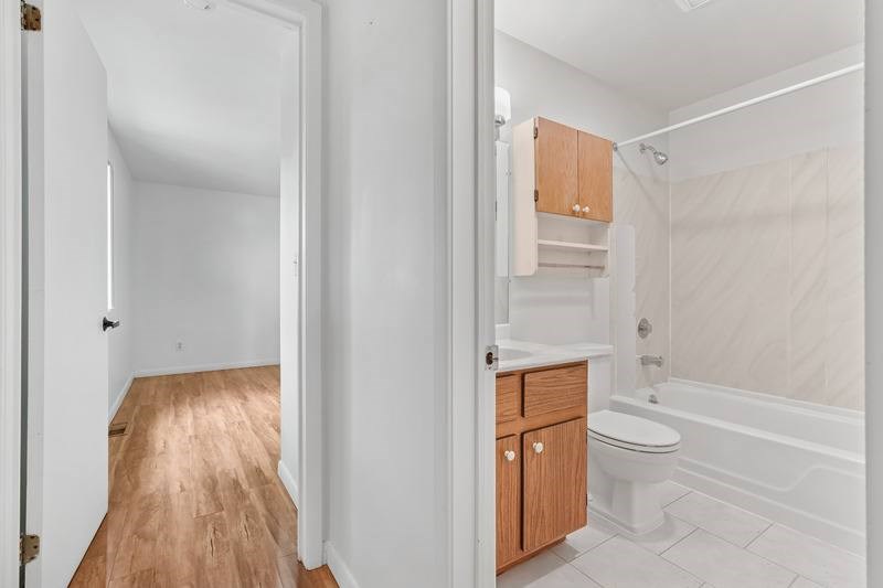 A white bathroom with wooden floors and a white toilet.