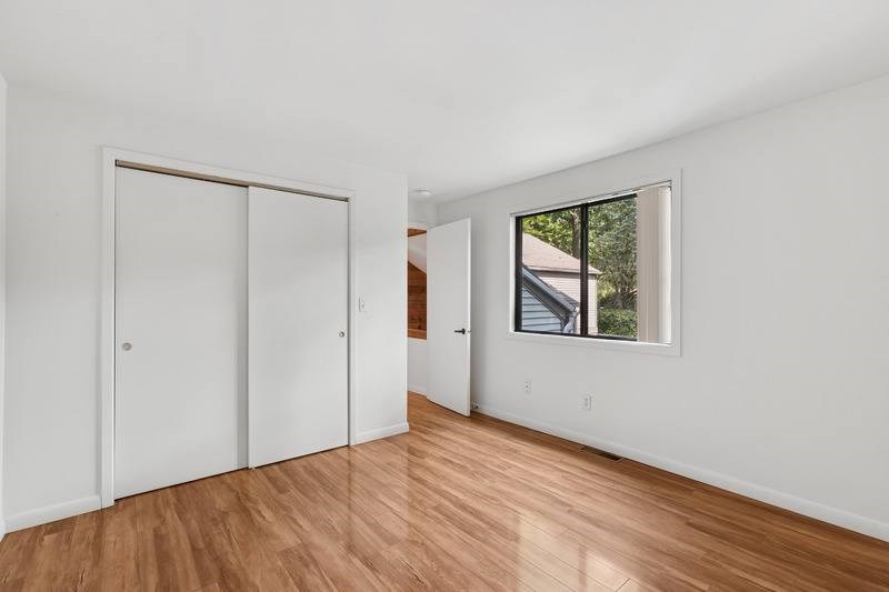 A room with a white wall and a window showing a balcony.