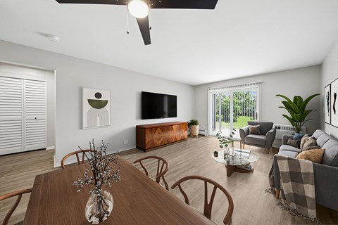 A modern living room with a wooden dining table and brown chairs.