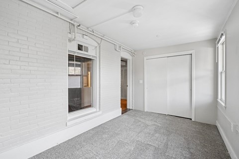 A room with a white wall and a grey carpet.