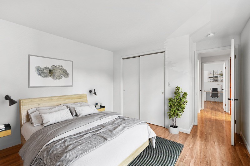A bedroom with a large bed and a plant on the side table.