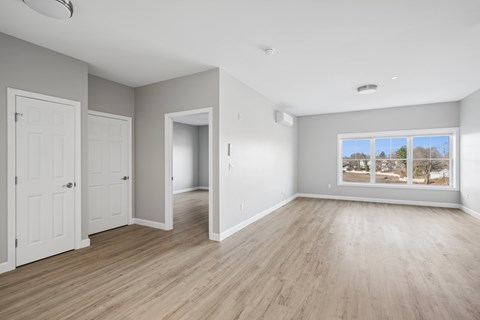 A spacious room with wooden flooring and a large window.