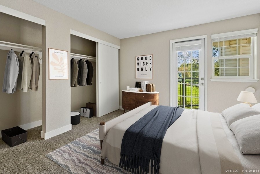 A bedroom with a bed, a dresser, and a window with a view of trees.