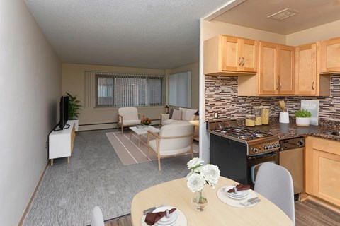 A well-lit kitchen and living room with a dining table set for two.
