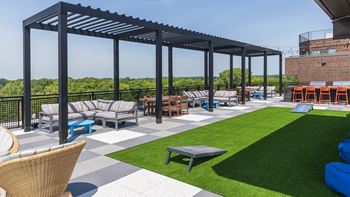 A patio with a black metal pergola and a variety of seating options.