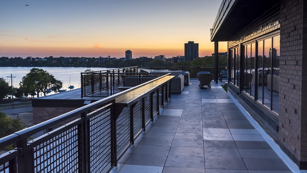 A balcony overlooks a body of water with a sunset in the background.