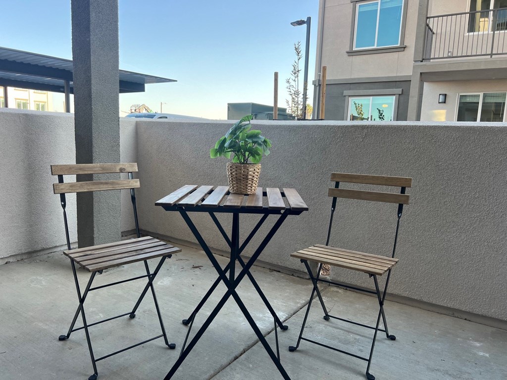 a table with two chairs and a plant on a balcony