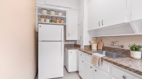 A white refrigerator is in a kitchen with a sink and counter.