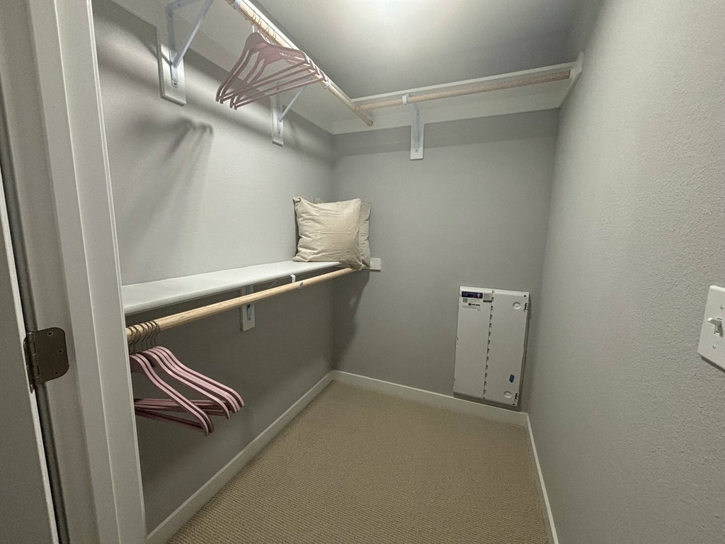 a walk in closet with a pillow on a shelf