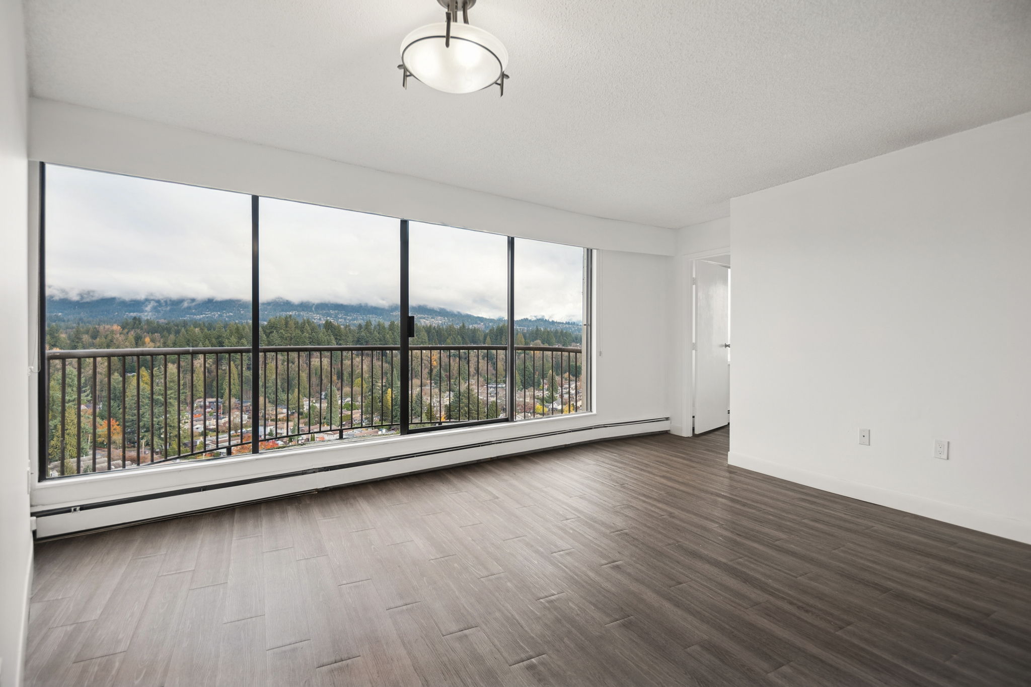 A large empty room with a view of the mountains outside the window.