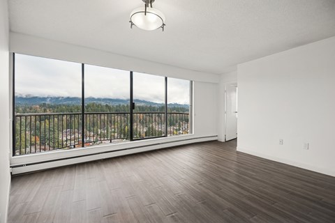 A large empty room with a view of the mountains outside the window.