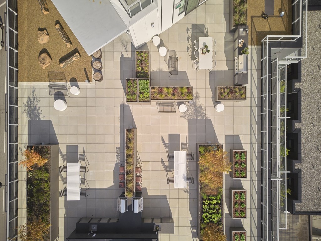 A top-down view of a courtyard with tables, chairs, and planters.