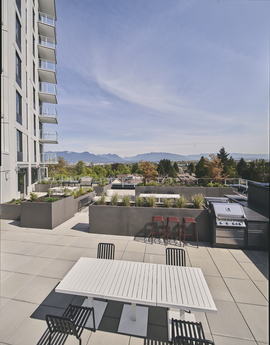 A white table and chairs are on a patio with a view of mountains.