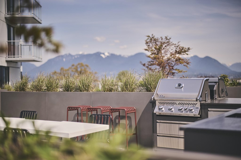A barbecue grill is on a patio with a table and chairs.