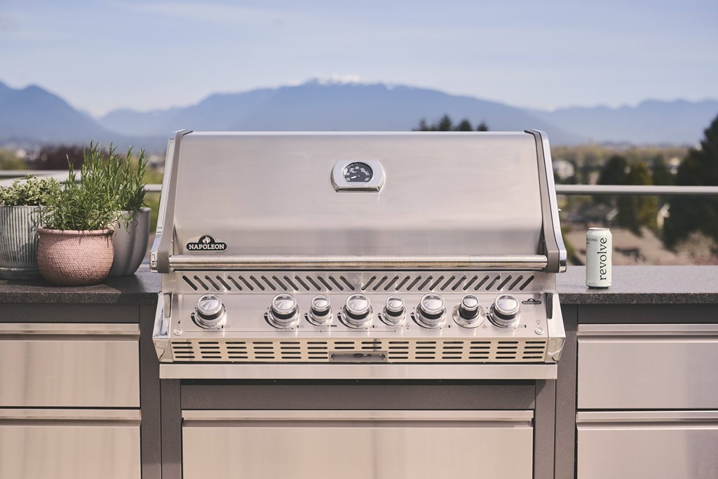 A gas grill on a balcony with a mountain view in the background.