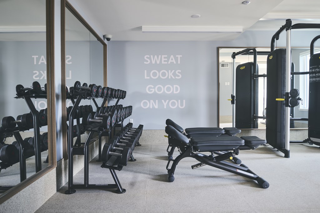 A gym with a mirror, weights, and a bench with the words