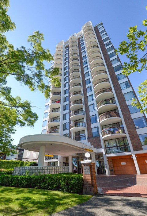 A tall residential building with balconies and a small entrance area.
