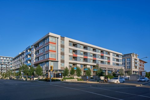 A modern multi-story building with a parking lot in front.