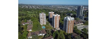A bird's eye view of a residential area with tall buildings and houses surrounded by trees.