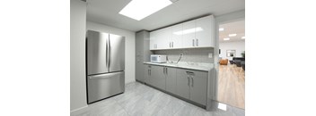 A modern kitchen with a stainless steel refrigerator and cabinets.
