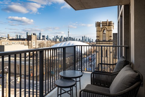 A balcony with a table and two chairs overlooking a cityscape.