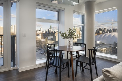A dining room with a table and chairs and a view of the city.