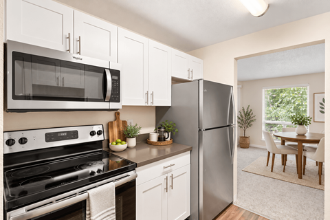A kitchen with white cabinets and a black microwave.
