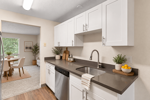 A kitchen with white cabinets and a black countertop.