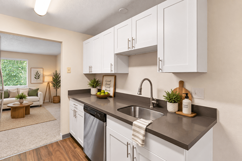 A kitchen with white cabinets and a black countertop.