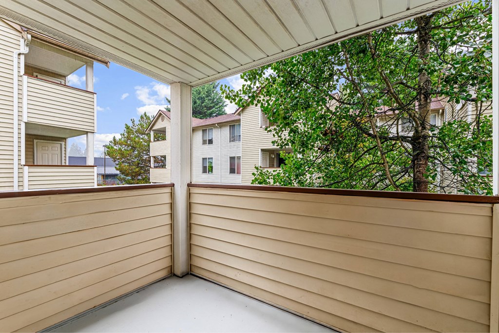 A balcony with a white ceiling and tan siding.