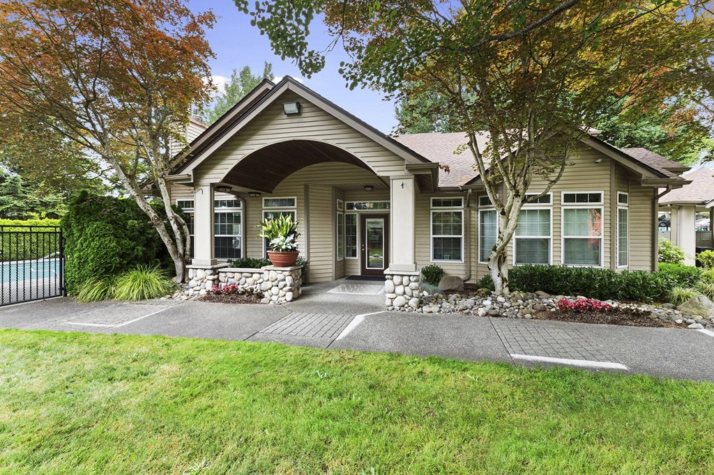 A house with a front yard and a tree with orange leaves.
