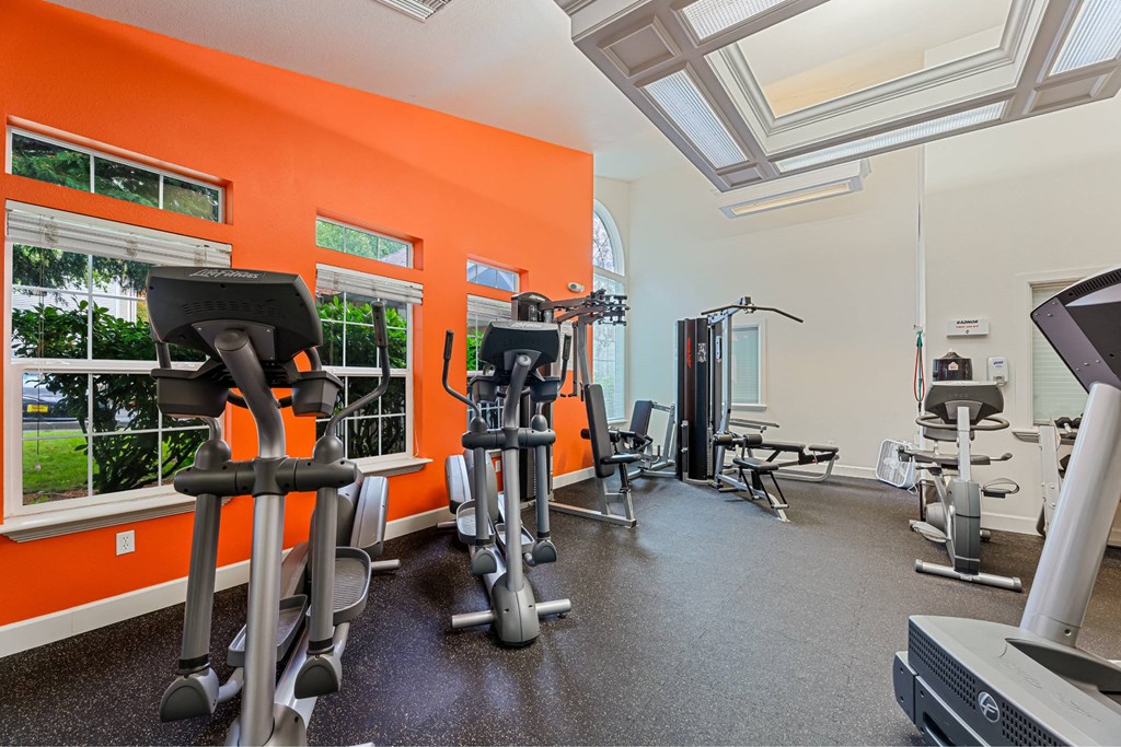 A gym with orange walls and various exercise machines.