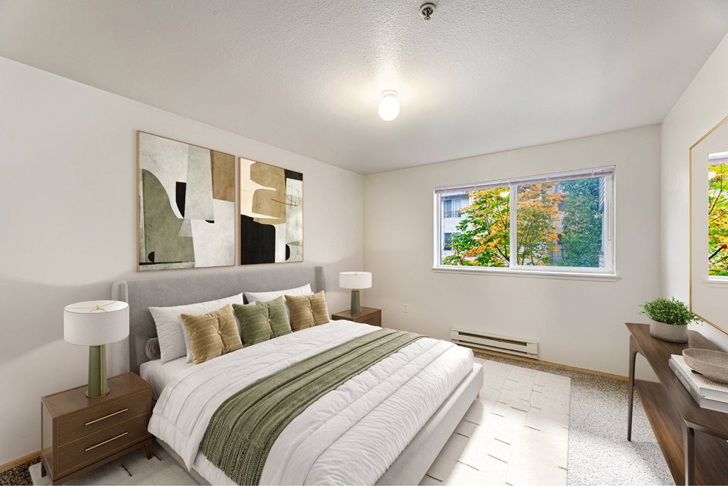 A bedroom with a large bed and a window showing trees outside.