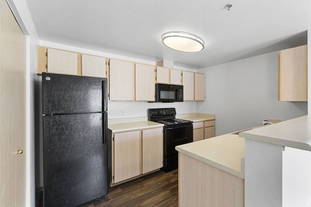 A kitchen with a black refrigerator, microwave, and stove.