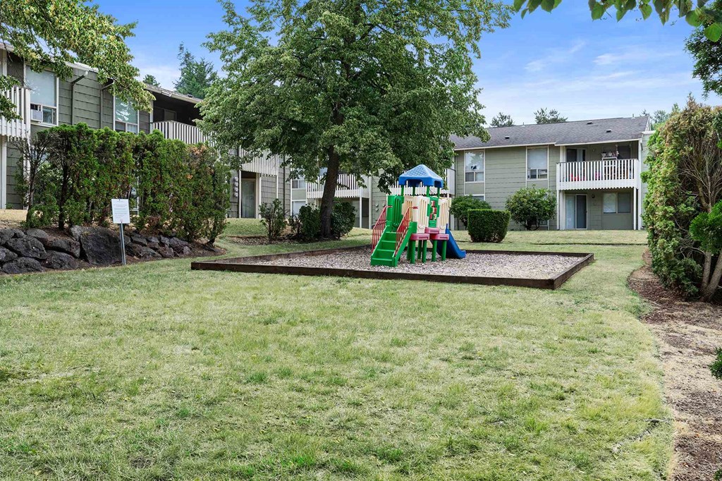 A playground with a slide and a green swing set.