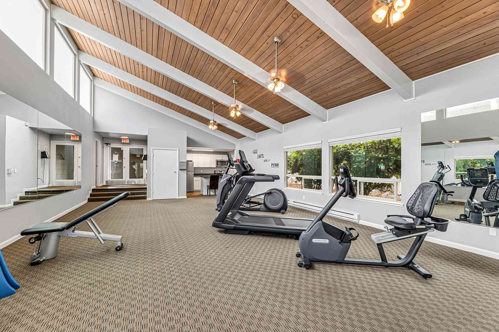 A gym with a variety of equipment including treadmills and weights.