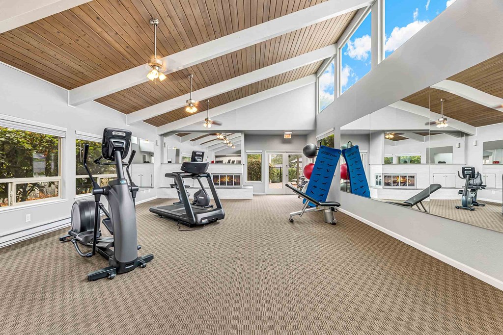A spacious gym with a variety of equipment including treadmills, stationary bikes, and weight machines.