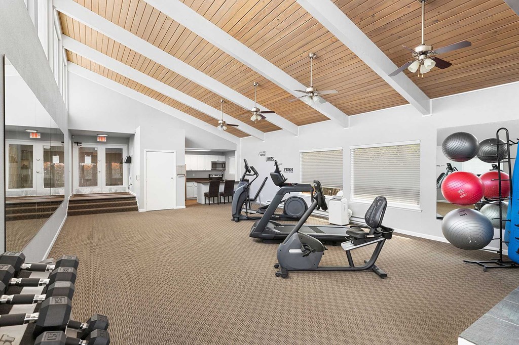 A gym with a variety of equipment including weights and exercise balls.