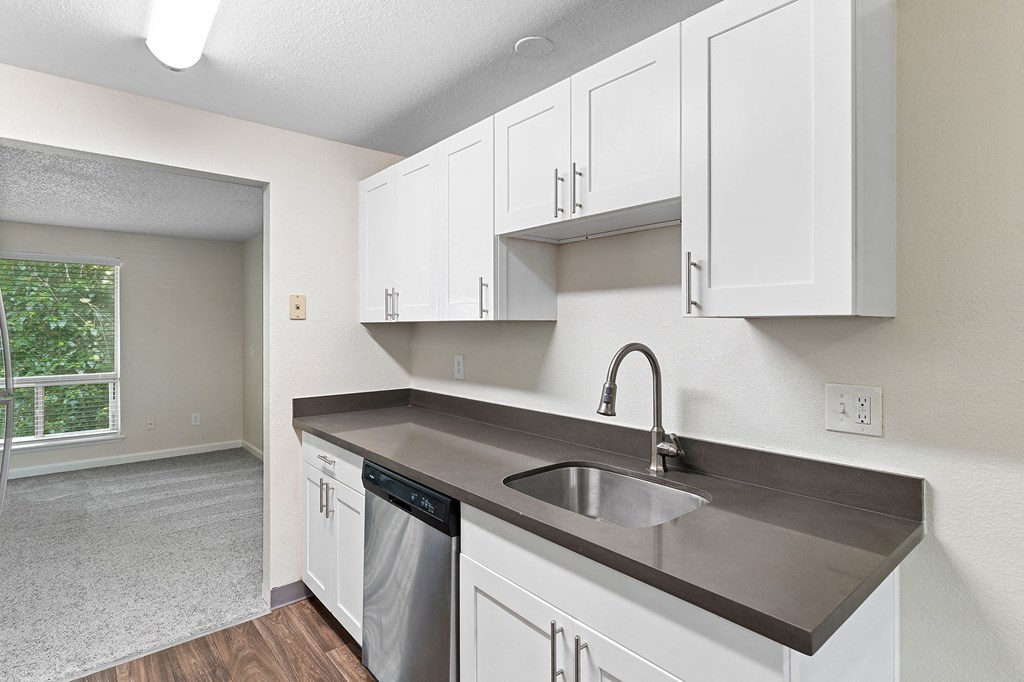 A kitchen with a stainless steel sink and white cabinets.