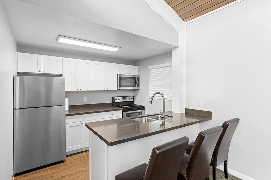 A modern kitchen with a stainless steel refrigerator and a granite countertop.