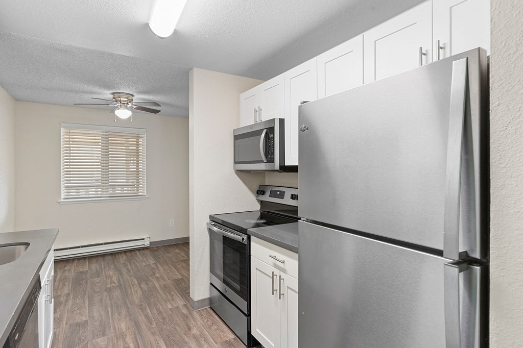 A kitchen with a refrigerator, microwave, oven, and sink.