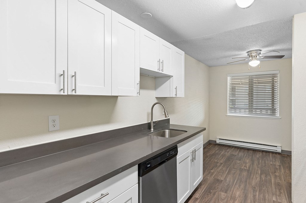 A kitchen with white cabinets and a stainless steel counter.