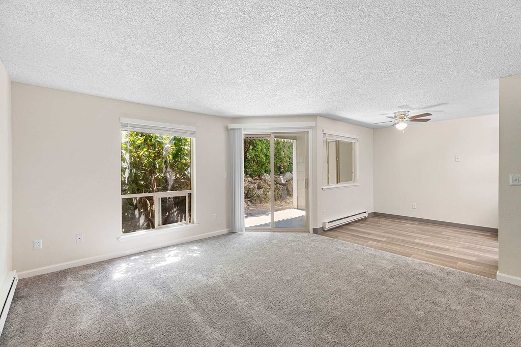 A spacious room with a carpeted floor and a ceiling fan.