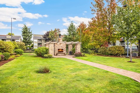 A sunny day in a well-kept garden with a stone fireplace.