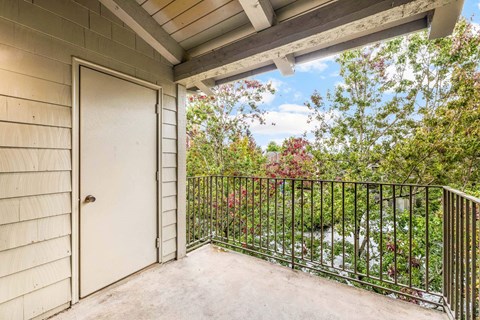 A balcony with a white door and a black railing.