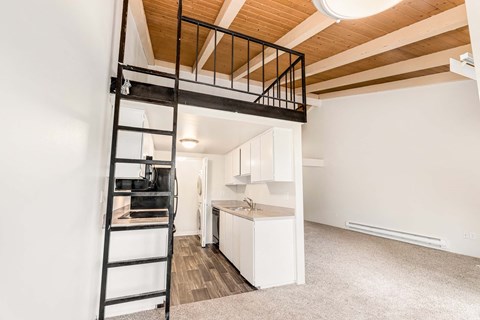 A white kitchen with a black metal staircase leading to the upper floor.