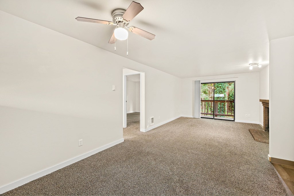 A room with a ceiling fan and carpeted floor.