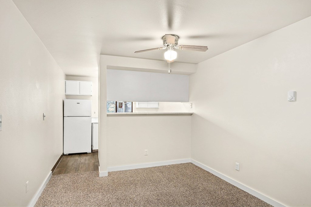 A room with a ceiling fan and a window with blinds.