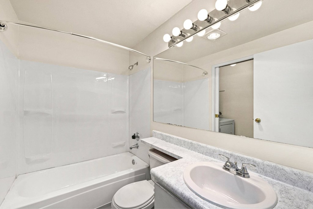 A white bathroom with a toilet, sink, and bathtub.
