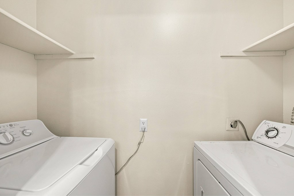 Two white washing machines in a laundry room.